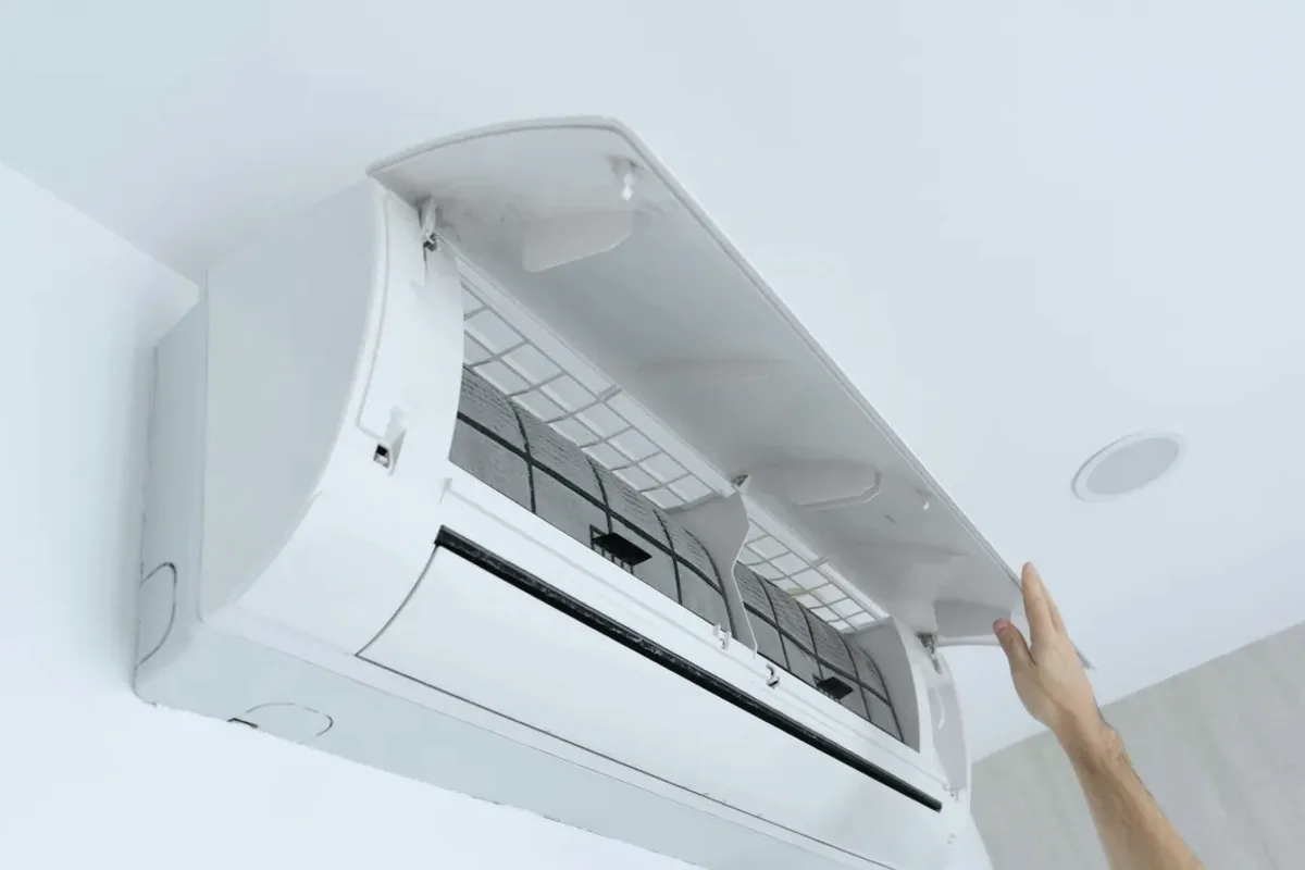 Hand opening the cover of a wall-mounted ductless air conditioner